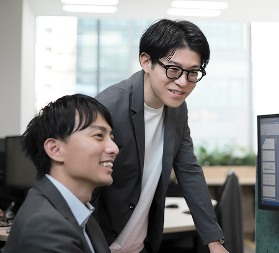 同僚と話しながら仕事をしているT.Kさんの様子